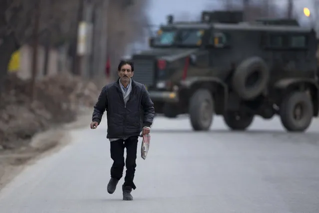 A Kashmiri civilian runS for safety after he along with others was evacuated from a government building, on the outskirts of Srinagar, Indian controlled Kashmir, Saturday, February 20, 2016. (Photo by Dar Yasin/AP Photo)