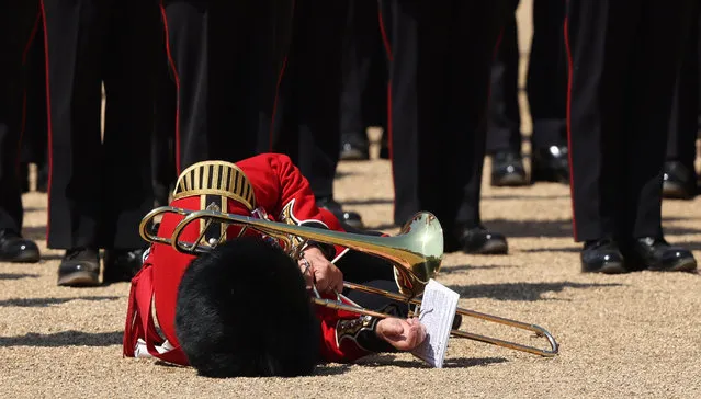 A trombone player faints as the band marches during the Colonel's Review at Horse Guards Parade in London on June 10, 2023 ahead of The King's Birthday Parade. The Colonel's Review is the final evaluation of the parade before it goes before Britain's King Charles III during the Trooping of the Colour on June 17. (Photo by Adrian Dennis/AFP Photo)