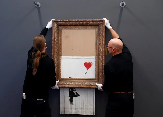 Employees of the Frieden Burda museum put Banksy's partially shredded artwork “Love is in the bin” in place at the museum in Baden Baden, Germany, February 4, 2019. (Photo by Kai Pfaffenbach/Reuters)