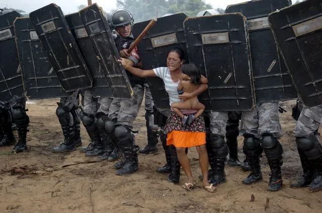 An indigenous woman holds her child while trying to resist the advance of Amazonas state policemen who were expelling the woman and some 200 other members of the Landless Movement from a privately-owned tract of land on the outskirts of Manaus, in the heart of the Brazilian Amazon, in this March 11, 2008 file photo. (Photo by Luiz Vasconcelos-A Critica/Reuters/AE)