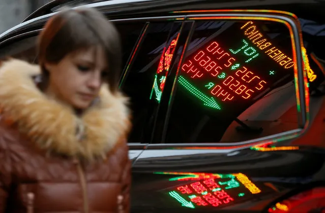 A board showing currency exchange rates is reflected in a car window as a woman walks by in Kiev, Ukraine December 29, 2016. (Photo by Valentyn Ogirenko/Reuters)