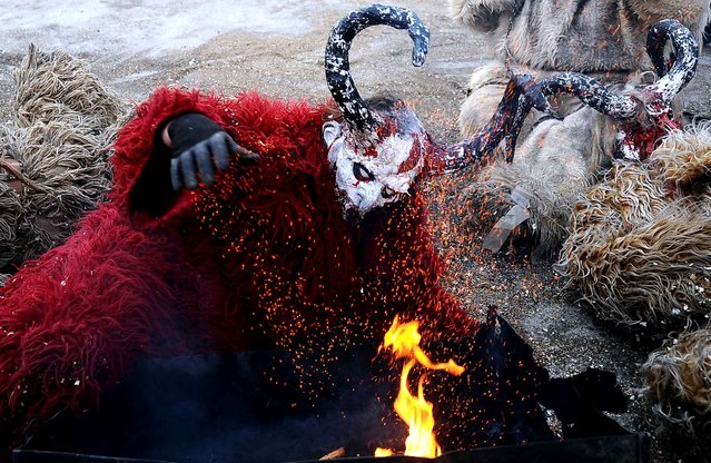 Disguised revelers stand next to a fire during the traditional mask burning ceremony on the second day of a carnival marking the Orthodox Saint Basil Day in the village of Vevchani, some 170 km from Skopje on January 14, 2014.The Vevchani carnival is 1,400 years old and is held every year on the eve of the feast of Saint Basil (14 January), which also marks the beginning of the New Year according to the Julian calendar, observed by the Macedonian Orthodox Church. (Photo by Robert Atanasovski/AFP Photo)