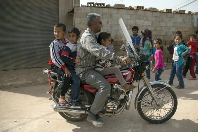 A man carries children on a bike to receive food aid from the Russian military in Maarzaf, about 15 kilometers west of Hama, Syria, Wednesday, March 2, 2016. (Photo by Pavel Golovkin/AP Photo)