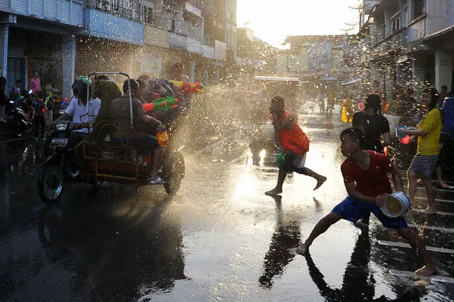 Chinese community people throw water on each other with buckets full of water during Water War Festival (Cian Cui) on January 29, 2017 in Selat Panjang, Indonesia. People participate in water fight festival, which includes playing with a toy water pistol to shoot at each other. The festival is held for six days starting on the first day of Chinese Lunar New Year. (Photo by Jefta Images/Barcroft Images)