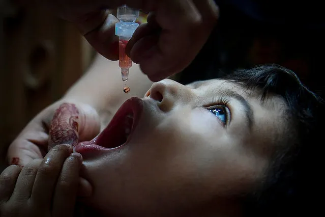 A health worker administers polio vaccine drops to a child during a polio vaccination campaign in Karachi on September 21, 2021. (Photo by Asif Hassan/AFP Photo)