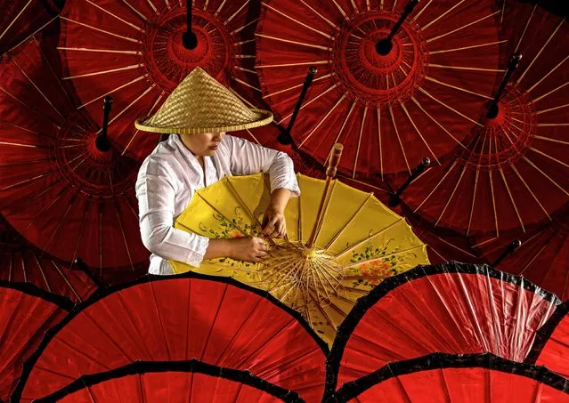 A worker is seen amongst vibrant umbrellas made from bamboo and paper early February 2024. The decorative parasols were being made in the village of Sindang Barang, Indonesia. Muljati Hidajat, 61, said “Here they are decorating the umbrellas. Several regions in Indonesia make these hand-decorated paper umbrellas. They are usually sold locally but people rarely use them as they are often for decoration”. (Photo by Muljati Hidajat/Solent News & Photo Agency)