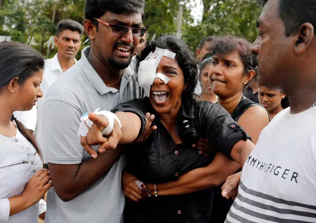 Kumari Fernando, who lost her husband, Dulip Fernando, and two children, Dulakghi and Vimukthi, during the bombing at St Sebastian's Church, yells towards the graves during a mass burial for victims at a cemetery near the church in Negombo, three days after a string of suicide bomb attacks on churches and luxury hotels across the island on Easter Sunday, in Sri Lanka April 24, 2019. (Photo by Thomas Peter/Reuters)