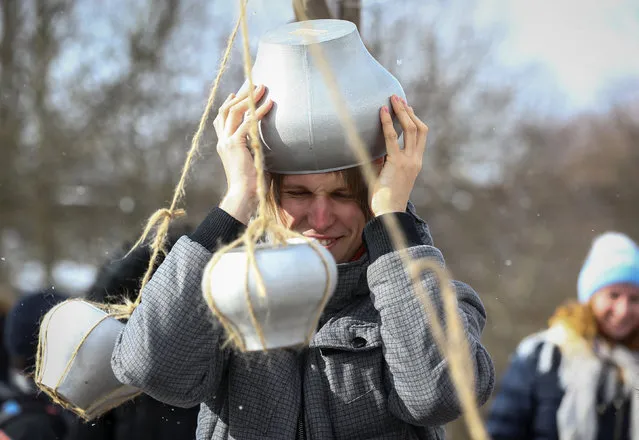 A man takes part in a festive game with cauldrons during celebration of Maslenitsa, or Pancake Week, in the Aziarco village, Belarus, February 25, 2017. (Photo by Vasily Fedosenko/Reuters)