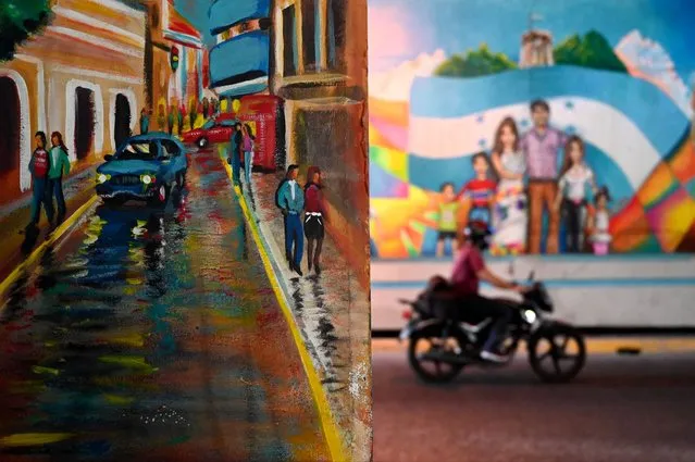 A motorcyclist rides past a mural on a central avenue in Tegucigalpa on February 8, 2024. The Honduran capital has become an open-air gallery, where local artists give color and life to this former mining town. (Photo by Orlando Sierra/AFP Photo)