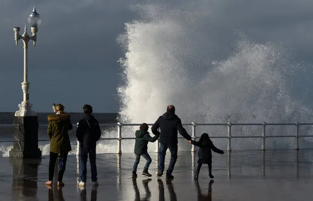 People react as waves crash against the seafront of San Lorenzo beach in Gijon, northern Spain, February 28, 2017. (Photo by Eloy Alonso/Reuters)