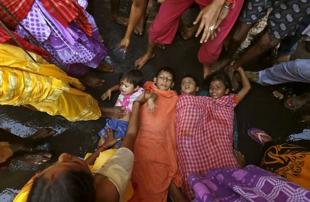 Children are made to lie on a road to get blessing from Hindu holy men who are passing by as part of a ritual to bless them during a religious procession to mark the Gajan festival in Kolkata, India, April 12, 2016. (Photo by Rupak De Chowdhuri/Reuters)