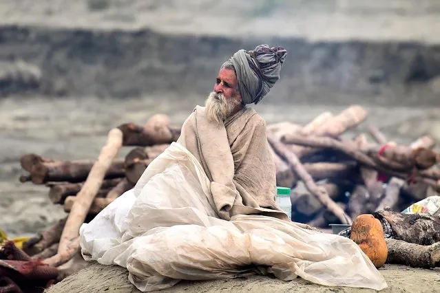 A Sadhu (holy man) sits as he arrives on the banks of the Sangam area, the confluence of rivers Ganges, Yamuna, and the mythical Saraswati, ahead of the upcoming Magh Mela festival, in Allahabad on December 29, 2021. (Photo by Sanjay Kanojia/AFP Photo)