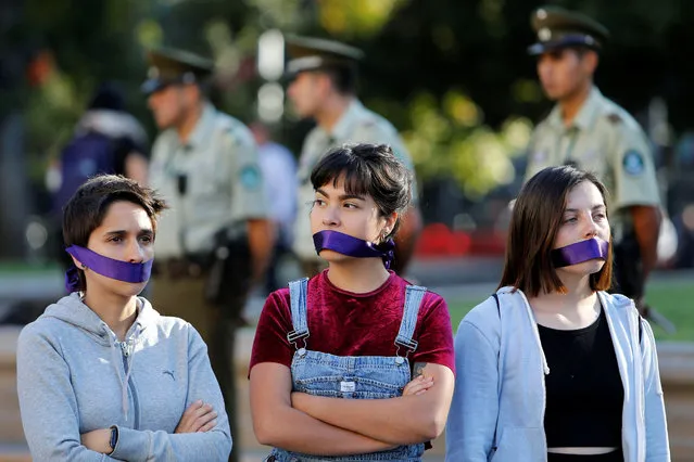 Women cover their mouths as they attend a peaceful demonstration in front of the government house as part of International Women's Day, in Santiago, Chile March 8, 2017. (Photo by Carlos Vera/Reuters)