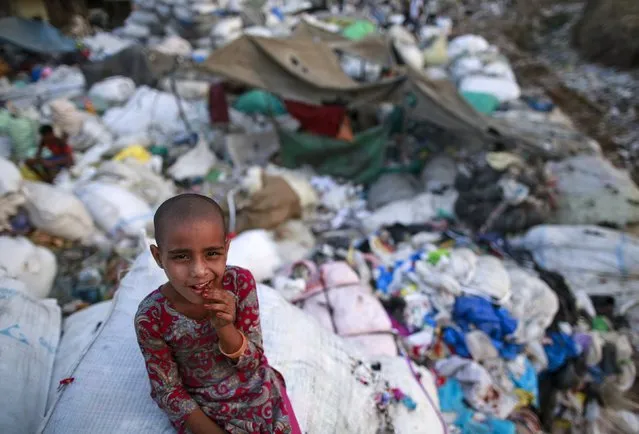 A girl sits on a sack of discarded clothes at a slum in Mumbai, India, April 20, 2016. (Photo by Danish Siddiqui/Reuters)
