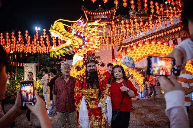  People take photos with God of Wealth after a Lunar New Year celebration at Thean Hou Temple on February 10, 2024, in Kuala Lumpur, Malaysia. Chinese New Year in Malaysia is marked by family gatherings, festive adornments and traditional rituals embodying a spirit of hope and renewal for the year ahead, and aims to bring joy and prosperity to all while fostering a sense of unity and hope for a successful Year of the Dragon. (Photo by Annice Lyn/Getty Images)