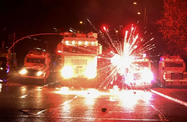 Fireworks explode at police vehicles after being fired at police officers with a water cannon during clashes with nationalist youths in the Springfield Road area of Belfast on April 8, 2021 as disorder continued in the Northern Ireland capital following days of mainly loyalist violence. Northern Ireland police faced a barrage of petrol bombs and rocks on on April 8, an AFP journalist said, as violence once again flared on the republican side of the divided city Belfast despite pleas for calm. (Photo by Paul Faith/AFP Photo)