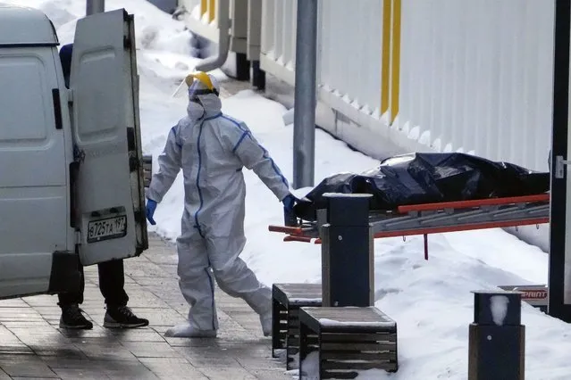 Medical workers carry a body to a van outside a COVID-19 hospital in Kommunarka, outside Moscow, Russia, Thursday, January 27, 2022. Russia's state coronavirus task force has reported more than 11.3 million confirmed cases and over 328 thousands deaths, by far the largest death toll in Europe. (Photo by Pavel Golovkin/AP Photo)