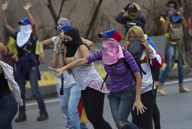 A group of women react as they see a line Bolivarian National Guard soldiers getting ready to launch a teargas during an anti-government protest in Caracas, Venezuela, Thursday, April 13, 2017. (Photo by Ariana Cubillos/AP Photo)
