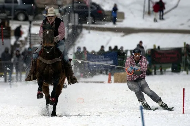 Rider Jeff Dahl (L) races down Harrison Avenue as skier and son Jason navigates the course during the 74th annual Leadville Ski Joring weekend competition on March 5, 2022 in Leadville, Colorado. Dahl has been competing as arider for 27 consecutive years and teams up with his sons. Skijoring, which has its origins as a competitive sport in Scandinavia, has been adapted over the years to include a team made up of a rider and skier who must navigate jumps, slalom gates, and the spearing of rings for points. Leadville, with an elevation of 10,152 feet (3,094 m), the highest incorporated city in North America, has been hosting skijoring competitions since 1949. (Photo by Jason Connolly/AFP Photo)