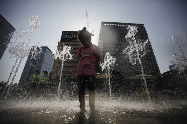 A girl plays in a fountain during a sunny day at a plaza in central Seoul May 14, 2014. (Photo by Kim Hong-Ji/Reuters)