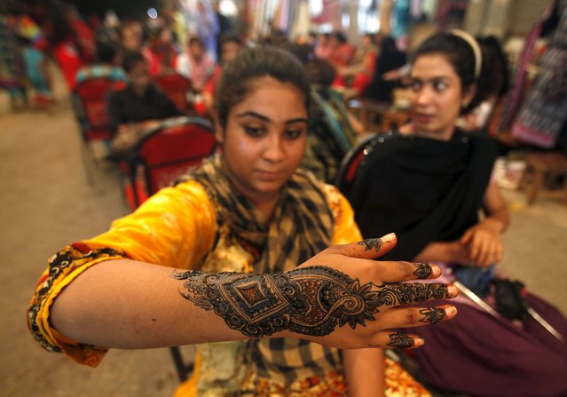 A girl shows her hand decorated with traditional henna patterns at a roadside stall ahead of Eid-al Fitr to mark the end of the holy fasting month of Ramadan in Karachi, Pakistan, July 17, 2015. (Photo by Akhtar Soomro/Reuters)