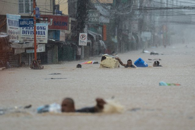 People wade through a flooded road following heavy rains brought by Typhoon Gaemi, in Marikina City, Metro Manila, Philippines, on July 24, 2024. (Photo by Lisa Marie David/Reuters)