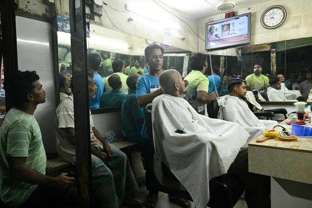 Customers watch on television the swearing in of Bangladesh's finance pioneer Muhammad Yunus at a barber shop in Dhaka on August 8, 2024. Nobel Peace Prize winner Muhammad Yunus was sworn into office on Ausgust 8, 2024 to lead Bangladesh's interim government as its chief adviser, days after a student-led uprising ended the 15-year rule of Sheikh Hasina. (Photo by Indranil Mukherjee/AFP Photo)