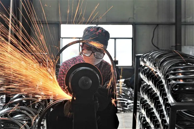 This photo taken on April 17, 2022 shows a worker welding wheels at a factory in Hangzhou in China's eastern Zhejiang province. (Photo by AFP Photo/China Stringer Network)