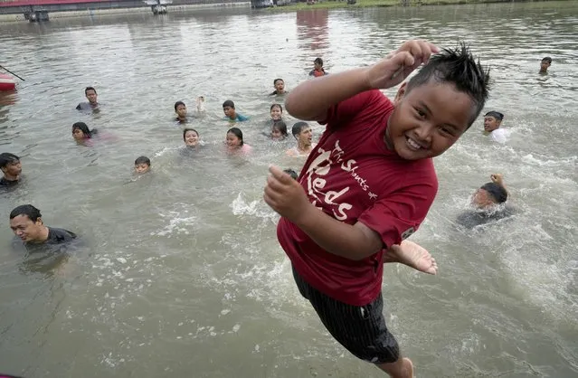 People bathe in the Cisadane River on the first evening of the holy fasting month of Ramadan in Tangerang, Indonesia, Saturday, April 2, 2022. Muslims followed local tradition to wash in the river to symbolically cleanse their soul prior to entering the holiest month in Islamic calendar. (Photo by Tatan Syuflana/AP Photo)