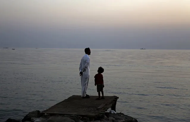 A Bahraini man and his son look for the new moon that marks the start of the Islamic holy month of Ramadan along the the Persian Gulf coast, in Karzakan, Bahrain, Sunday, June 5, 2016. Bahrain announced that Monday would be the first day of the Islamic month of Ramadan, a time Muslims worldwide focus on prayer, fasting and charitable giving. (Photo by Hasan Jamali/AP Photo)