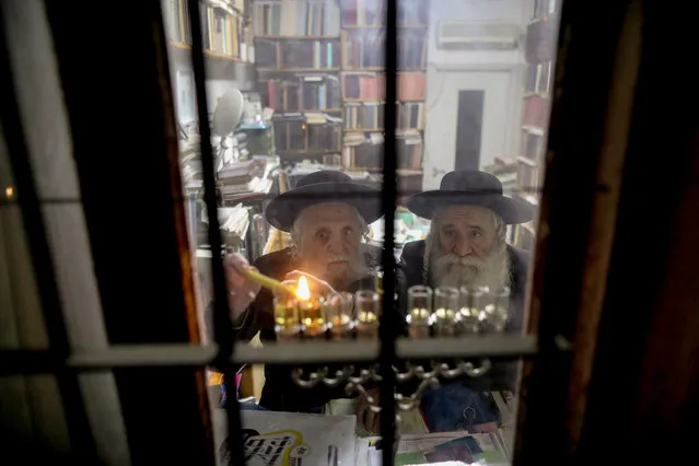 Ultra-Orthodox Jews light a Hanukkah candle inside their house during the Jewish holiday of Hanukkah in the Mea Shearim neighbourhood of Jerusalem, Israel, 23 December 2019. Hanukkah, also known as the “Festival of Lights”, is one of the most important Jewish holidays and is celebrated by Jews worldwide. This year, Hanukkah began in the evening of 22 December 2019 and ends in the evening of 30 December 2019. (Photo by Abir Sultan/EPA/EFE)
