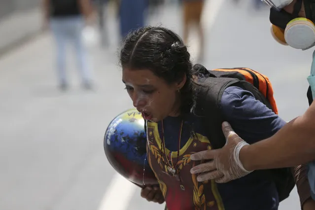 A woman chocking on tear gas, is aided by a fellow anti-government demonstrator during clashes with security forces in Caracas, Venezuela, Monday, June 19, 2017. (Photo by Fernando Llano/AP Photo)
