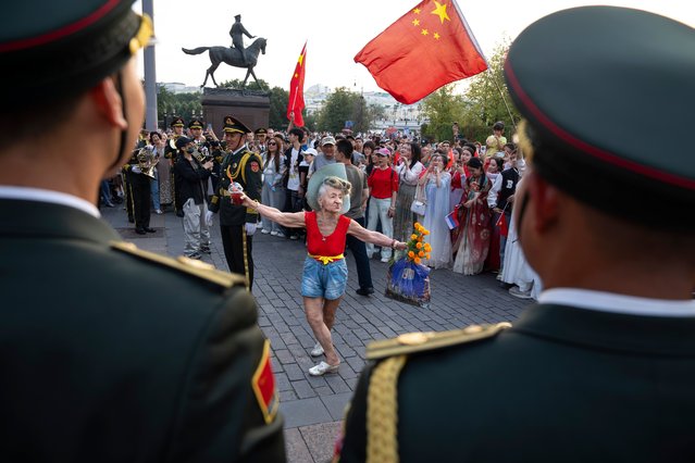 An elderly woman dances while the Military Band of the Chinese People's Liberation Army perform at the Historical Museum prior to the closing of Spasskaya Tower International Military Music Festival in Red Square, with the statue of Soviet Marshal Georgy Zhukov in the background, in Moscow, Russia, Sunday, September 1, 2024, with foreign participants include Belarus, Venezuela, Egypt, China, Thailand, Turkey, South Africa and Guinea. (Photo by Alexander Zemlianichenko/AP Photo)