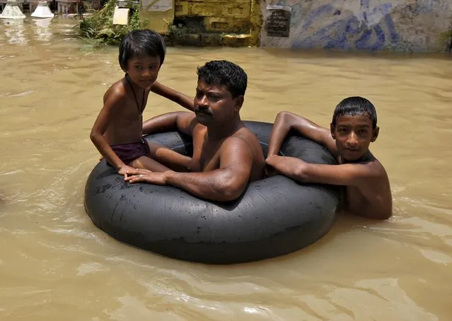Flood-affected people use a tyre tube as they move to safer grounds through the flood waters at West Midnapore district in West Bengal, India, August 4, 2015. At least 75 people have died and tens of thousands have had to take refuge in state-run relief camps after heavy rains caused floods and landslides in eastern India, government officials and aid groups said on Monday. (Photo by Rupak De Chowdhuri/Reuters)
