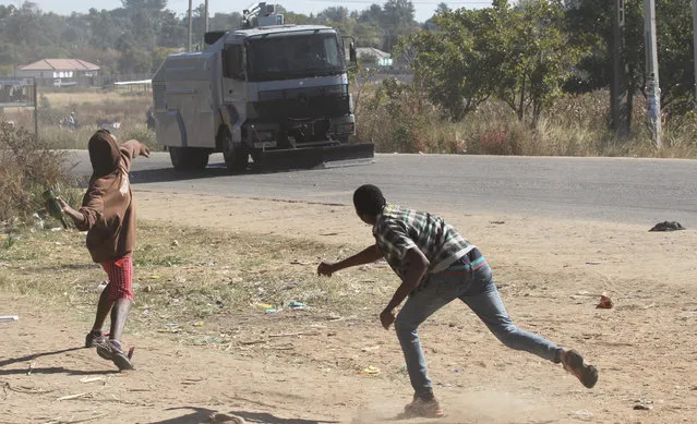 Rioters battle with Zimbabwean police in Harare, Monday, July, 4, 2016. Police in Zimbabwe's capital fired tear gas and water cannons in an attempt to quell rioting by taxi and mini bus drivers protesting what they describe as police harassment.  The violence came amid a surge in protests in recent weeks because of economic hardships and alleged mismanagement by the government of President Robert Mugabe. (Photo by Tsvangirayi Mukwazhi/AP Photo)