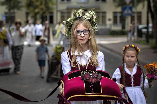 Girls take part in an emotional procession following the icon of the Virgin Mary during the feast day of the Assumption of Mary in the small town Trakai, some 30km (18 miles) west of the capital Vilnius, Lithuania, Tuesday, August 15, 2023. Lithuania is celebrating the day of the Assumption of the Blessed Virgin Mary which is a national holiday. (Photo by Mindaugas Kulbis/AP Photo)