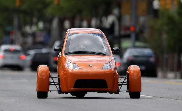 The Elio, a three-wheeled prototype vehicle, is shown in traffic in Royal Oak, Mich., Thursday, August 14, 2014. Instead of spending $20,000 on a new car, Paul Elio is offering commuters a cheaper option to drive to work. His three-wheeled vehicle The Elio will sell for $6,800 car and can save on gas with fuel economy of 84 mpg. (Photo by Paul Sancya/AP Photo)
