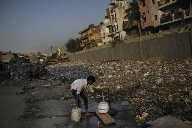 In this Tuesday, March 17, 2020 photo, a slum dweller fills water from a tap next to a drain filled with plastic and other filth in New Delhi, India. Experts say keeping hands clean is one of the easiest and best ways to prevent transmission of the coronavirus, in addition to social distancing. But for India’s homeless and urban poor who live in thousands of slums across major cities and towns, maintaining good hygiene can be nearly impossible. (Photo by Altaf Qadri/AP Photo)