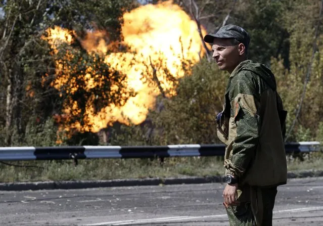 An armed pro-Russian separatist looks as flames erupt from a gas pipeline after a shelling in Donetsk, August 15, 2014. (Photo by Sergei Karpukhin/Reuters)