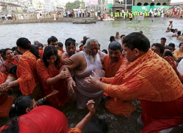 A Sadhu or Hindu holy man is helped by devotees after taking a dip in the Godavari river during the first Shahi Snan (grand bath) at Kumbh Mela, or Pitcher Festival in Nashik, India, August 29, 2015. (Photo by Danish Siddiqui/Reuters)