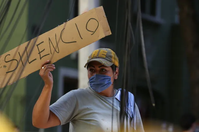 A woman holds a sign the reads in Spanish “Silence” as first responders work on removing the rubble of a collapsed building looking for survivors trapped underneath, after a 7.1 earthquake in Mexico City, Tuesday, September 19, 2017. (Photo by Gustavo Martinez Contreras/AP Photo)