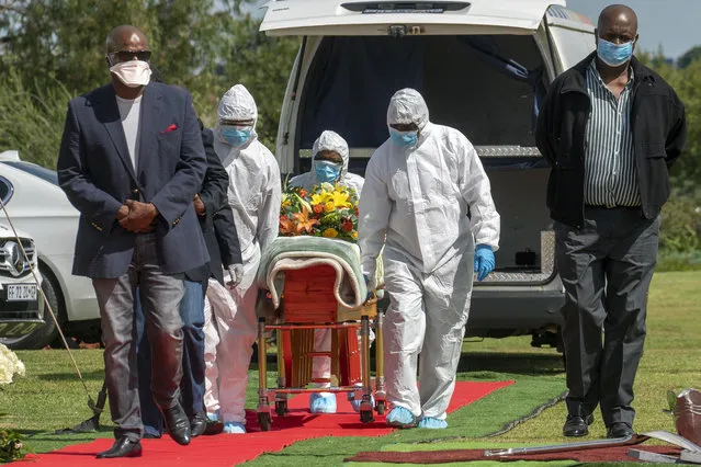 Pallbearers wearing full PPE suits lift the casket containing the remains of Benedict Somi Vilakasi for his burial ceremony at the Nasrec Memorial Park outside Johannesburg Thursday, April 16, 2020. Vilakasi, a Soweto coffee shop manager, died of Covid-19 infection in a Johannesburg hospital Sunday April 12 2020. South Africa is under a strict five-week lockdown in a effort to fight the Coronavirus pandemic. (Photo by Jerome Delay/AP Photo)