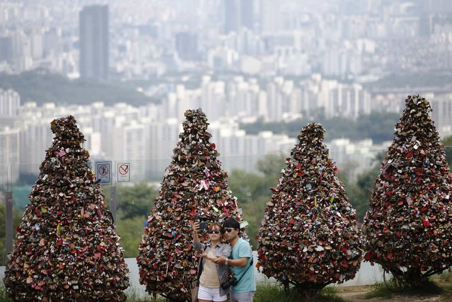 A couple takes a selfie in front of trees covered with “love locks” at N Seoul Tower located atop Mt. Namsan in central Seoul August 29, 2014. The terrace has become famous for padlocks left by couples to symbolise their affection. (Photo by Kim Hong-Ji/Reuters)