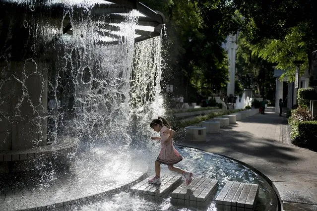 A young girl run under a water fountain on a hot summer day in Hong Kong on August 26, 2014. The Hong Kong Observatory issued a hot weather warning as temperatures reached 34 degrees Celsius (93 degrees Fahrenheit) in the southern Chinese city. (Photo by Alex Ogle/AFP Photo)