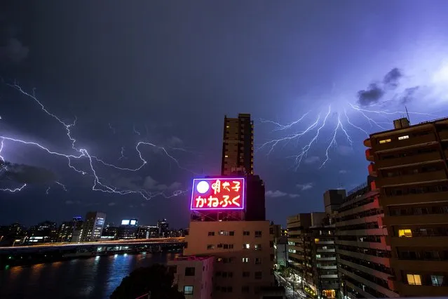 This long exposure photo shows lightning over the Koto district of Tokyo on July 28, 2022. (Photo by Philip Fong/AFP Photo)