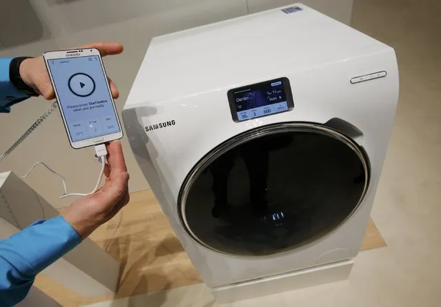 A Samsung employee holds a smartphone remotely controlling a WW9000 washing machine at the IFA consumer technology fair in Berlin, September 5, 2014. (Photo by Fabrizio Bensch/Reuters)
