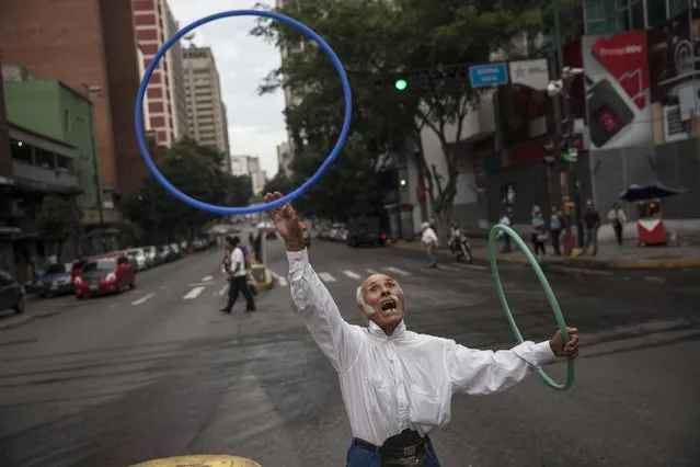 Jose Bestilleiro, 83, from Spain, performs for tips at an street intersection in downtown Caracas, Venezuela, Sunday, October 29, 2017. Bestilleiro said he's been performing every day for the past 15 years, and brings in at least 5,000 Bolivars a day, which on the black market is 11 cents and is the price of a cheap “arepa” sandwich. (Photo by Rodrigo Abd/AP Photo)