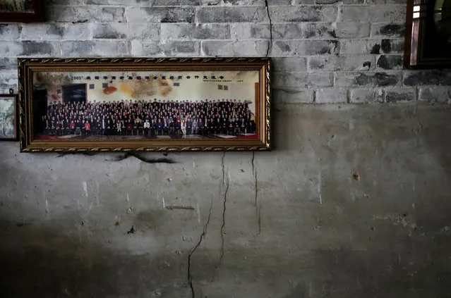A group photograph hangs on a damaged wall at Wang Junqi's cave house in an area where land is sinking next to a coal mine, in Helin village of Xiaoyi, Shanxi province, August 2, 2016. Deep in the coal heartlands of northern Shanxi province, people in Helin village are fighting a losing battle as the ground beneath them crumbles: patching up cracks, rebuilding walls and filling in sinkholes caused by decades of coal mining. Around 100 mines in Helin – buried in the hilly rural outskirts of the city of Xiaoyi – have been exhausted, and cluttered hamlets totter precariously on the brittle slopes of mining pits. (Photo by Jason Lee/Reuters)