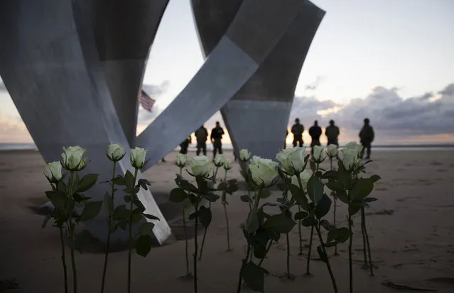 Men in a vintage US WWII uniforms stand behind flowers left at Les Braves monument after a D-Day 76th anniversary ceremony in Saint Laurent sur Mer, Normandy, France, Saturday, June 6, 2020. Due to coronavirus measures many ceremonies and memorials have been cancelled in the region with the exception of very small gatherings. (Photo by Virginia Mayo/AP Photo)