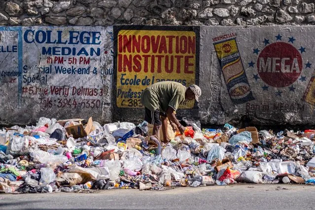 A man looks through piles of trash on the side of a street in Port-au-Prince, Haiti on October 16, 2022. (Photo by Ricardo Arduengo/Reuters)